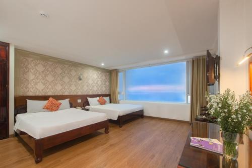 een hotelkamer met 2 bedden en een groot raam bij LE SOLEIL HOTEL managed by NEST Group in Nha Trang