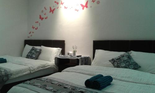 two beds in a room with birds on the wall at Best Seven Inn in Kuah