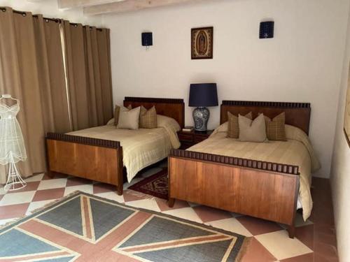 1 dormitorio con 2 camas y mesa con lámpara en Increible y Comoda Casa en el Campo, en Godínez