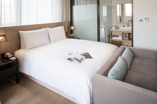 a bedroom with a large white bed and a couch at Riverview Suites Taipei in Taipei