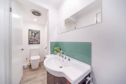 a white bathroom with a sink and a toilet at Spacious 3Bd n Pool family holiday home TF2223 in Frankston