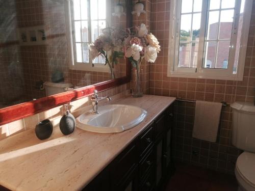baño con lavabo y jarrón de flores en Casa Rosita Relax - Piscina y gran terraza, en Aguadulce