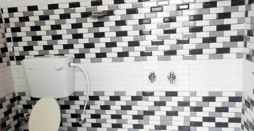 a bathroom with a toilet and a black and white tiled wall at Misty Mountains Holiday Homes in Vattavada