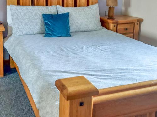 a bed with a blue pillow and a wooden headboard at Park Lodge in Strachan