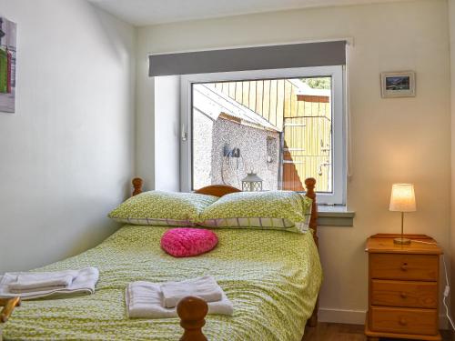 a bedroom with a bed with a large window at Glen Nevis Cottage in Port Elphinstone