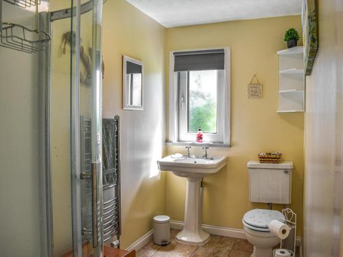 a bathroom with a sink and a toilet and a window at Glen Nevis Cottage in Port Elphinstone