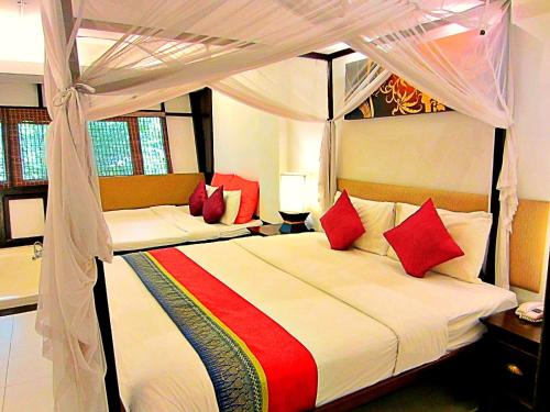 a bedroom with a canopy bed with red pillows at Yantarasri Resort in Chiang Mai