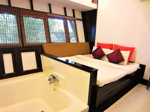 a bedroom with a tub and a bed with pillows at Yantarasri Resort in Chiang Mai