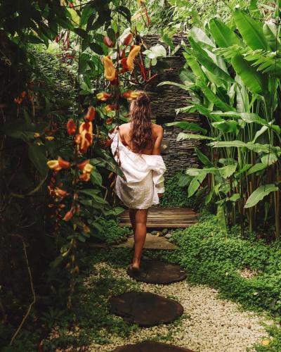 a woman in a white dress walking through a garden at Baba Yaga Atitlan in San Marcos La Laguna