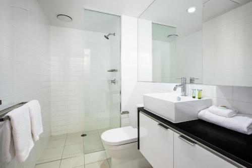 a white bathroom with a sink and a toilet at Code Apartments in Brisbane