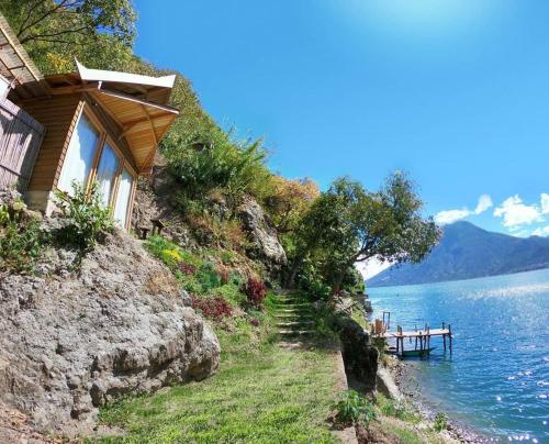 uma casa num penhasco ao lado de um corpo de água em Baba Yaga Atitlan em San Marcos La Laguna