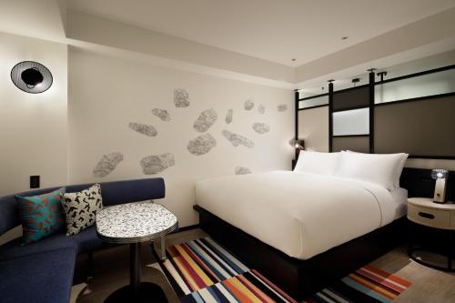 um quarto com uma cama branca e um sofá azul em Aloft Osaka Dojima em Osaka