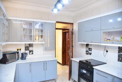 a kitchen with white cabinets and a black stove at K-Cube Villas in Kampala