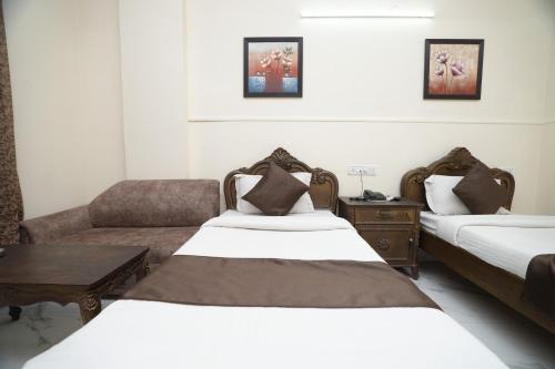 ニューデリーにあるHotel Silver Arc - Karol Bagh New Delhiのベッド2台とソファが備わるホテルルームです。