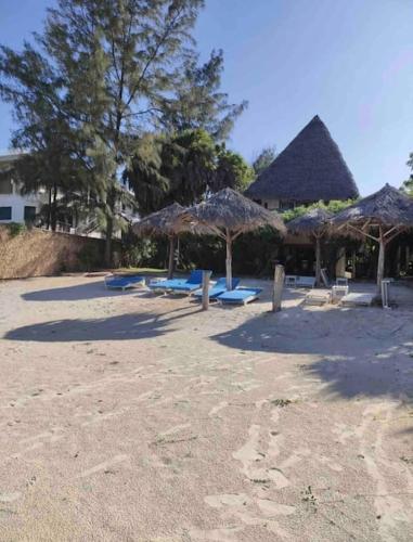 a group of straw umbrellas on a sandy beach at Cosy Cottage Marine Park at Malindi Beach in Malindi