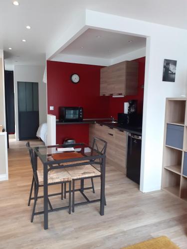 une table et des chaises dans une cuisine aux murs rouges dans l'établissement Mini Loft, à Saintes