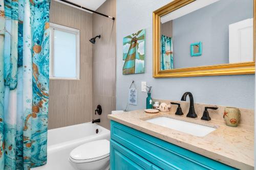 a bathroom with a sink and a toilet and a mirror at Vibrant Pool Home! Kayak, Firepit & Playground! in West Palm Beach