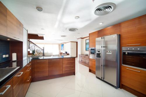 Patongtower Duplex Seaview4BR2902 في شاطيء باتونغ: مطبخ مع دواليب خشبية وثلاجة حديد قابلة للصدأ