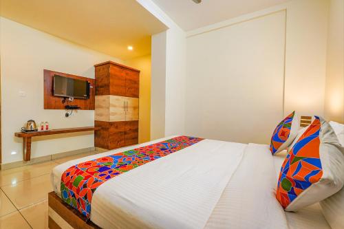 a bedroom with a bed and a tv on a wall at FabHotel Shakthi Suites - Nr Jayadeva Hospital in Bengaluru