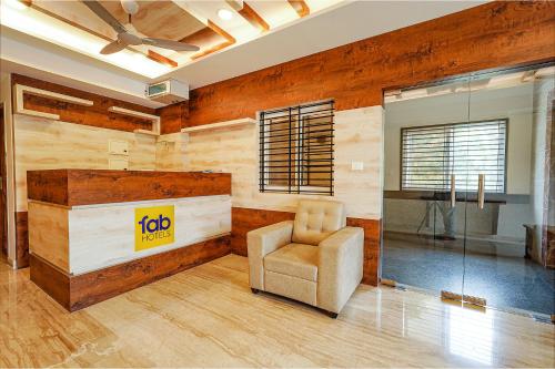 a living room with a chair and a sign on the wall at FabHotel Shakthi Suites - Nr Jayadeva Hospital in Bengaluru