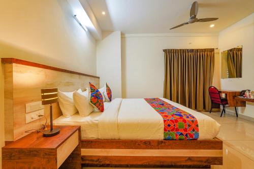a bedroom with a bed and a desk with a lamp at FabHotel Shakthi Suites - Nr Jayadeva Hospital in Bengaluru