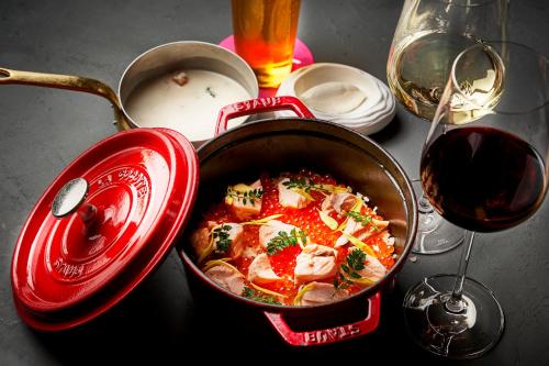 a pan of food in a red pot next to a glass of wine at Aloft Osaka Dojima in Osaka