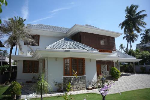 a white house with palm trees in front of it at Alite Posh 4 BHK Villa in Thrissur Town in Trichūr