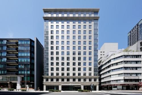 a tall white building with many windows in a city at Aloft Osaka Dojima in Osaka