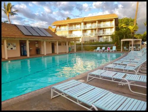 a swimming pool with lounge chairs in front of a hotel at Unrivaled S Kihei Maui location! Walk to it all! in Kihei