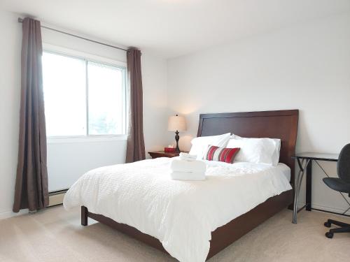 1 dormitorio con 1 cama blanca y ventana en Tranquil Retreat Spacious 2-Bedroom on a Serene Acreage, en Kelowna