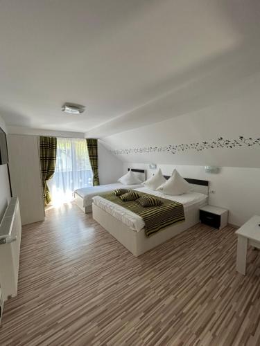 a white bedroom with two beds and a window at Casa Mia in Braşov