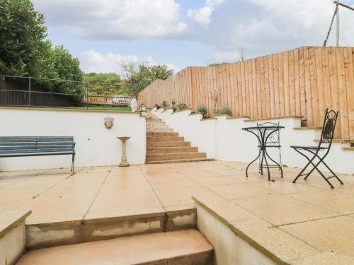 a patio with a bench and stairs and a fence at Celia's View in Langport