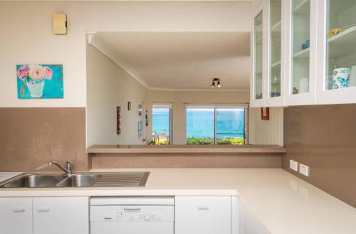 een keuken met een wastafel en uitzicht op de oceaan bij The Headland in Woolgoolga