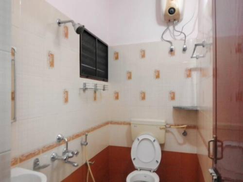 a bathroom with a toilet and a sink and a window at Aathira's 2 Bedroom house @ Heart of Coimbatore in Coimbatore