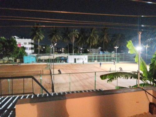 a tennis court at night with palm trees at Aathira's 2 Bedroom house @ Heart of Coimbatore in Coimbatore
