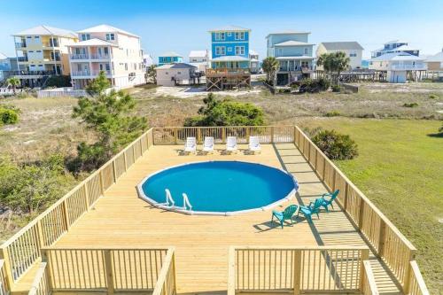 a deck with a pool and chairs and houses at The Herron, Sleep 20, Walk beach in Gulf Shores
