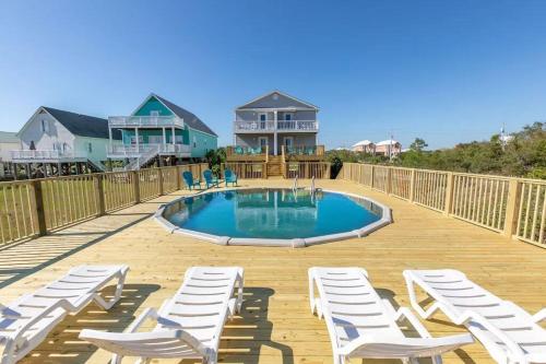 a deck with white chairs and a swimming pool at The Herron, Sleep 20, Walk beach in Gulf Shores