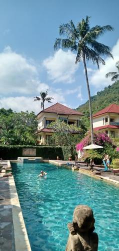 a person swimming in a swimming pool with a palm tree at Secret garden villa 5 # 3 in Mangsit