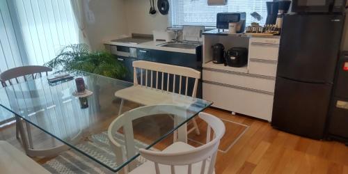 uma cozinha com uma mesa de vidro e cadeiras em Guest Room安曇野2466 em Hitoichiba