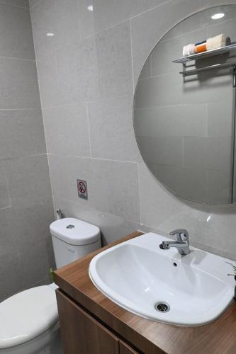 a bathroom with a sink and a mirror and a toilet at Apartment Medan Podomoro City Deli by OLS Studio in Medan