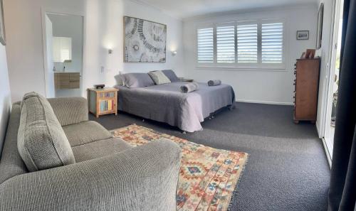 a bedroom with a bed and a couch and a chair at Cooinda in Woolgoolga