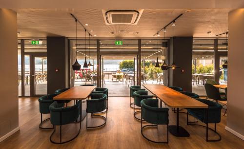 a restaurant with wooden tables and green chairs at Hotel Arka in Orşova