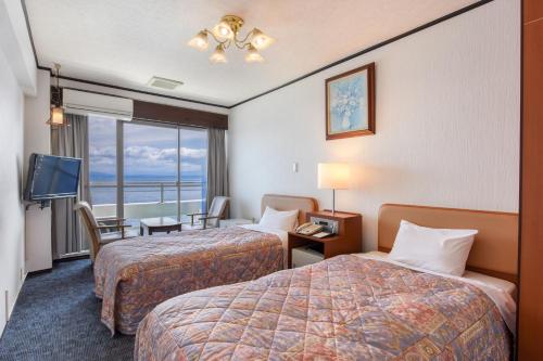 a hotel room with two beds and a view of the ocean at Ibusuki Kaijo Hotel in Ibusuki