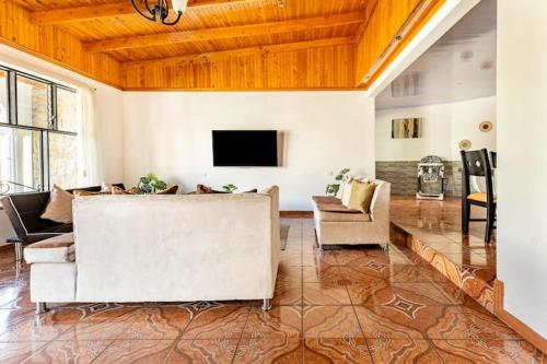 a living room with couches and a flat screen tv at Villa Dreams Irazu in Cartago