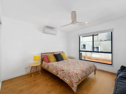 a white bedroom with a bed and a window at The Black House in Arrawarra
