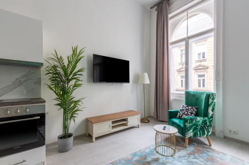 a living room with a green chair and a large window at LH Gallery Apartments in Budapest