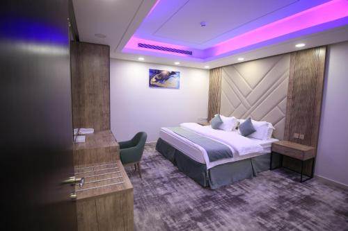 um quarto de hotel com uma cama e uma cadeira em شقق نيروز ان للشقق المخدومة - Newroz N Serviced Apartments em Riyadh