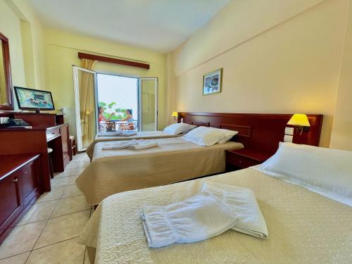 a hotel room with two beds and a window at Venardos Hotel in Agia Pelagia