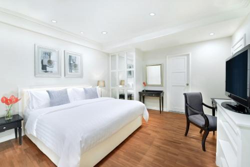 a white bedroom with a large bed and a television at Centre Point Chidlom in Bangkok