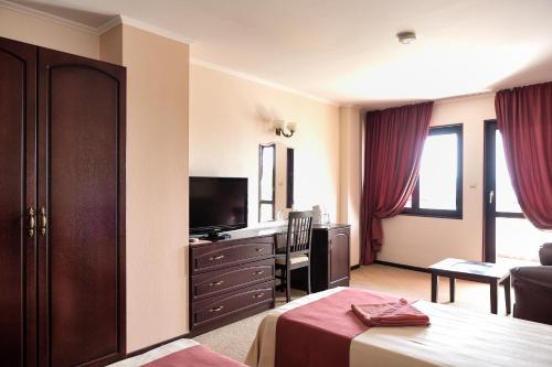 a hotel room with a bed and a television at House Diona in Sozopol